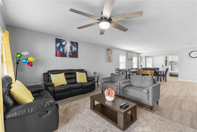 living room with ceiling fan, light wood finished floors, and baseboards