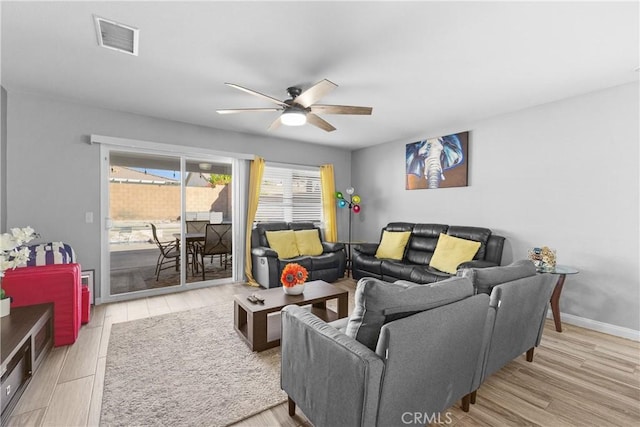 living room featuring a ceiling fan, visible vents, baseboards, and wood finished floors