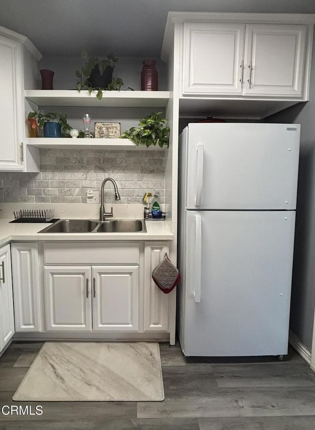 kitchen featuring white cabinetry, a sink, and freestanding refrigerator