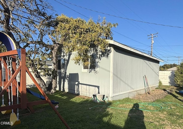 view of side of property with a playground, fence, and a lawn