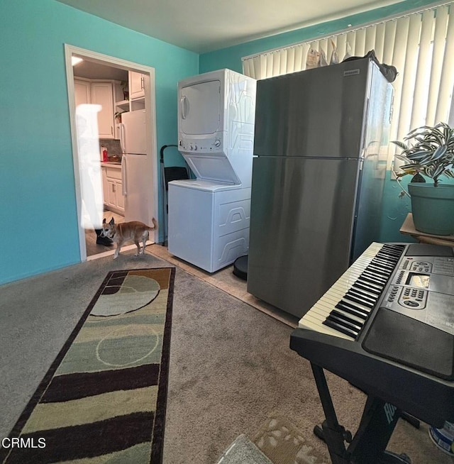 clothes washing area featuring laundry area, carpet, and stacked washer and clothes dryer