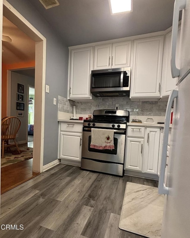 kitchen featuring stainless steel appliances, light countertops, decorative backsplash, dark wood-type flooring, and white cabinetry