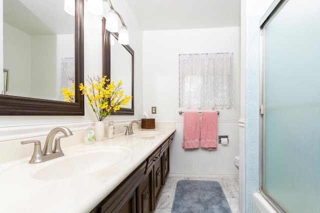 full bathroom with marble finish floor, double vanity, a sink, and toilet