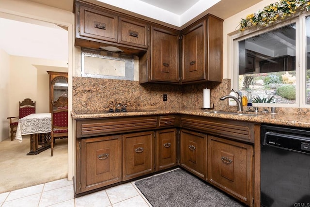 kitchen with light stone counters, backsplash, light tile patterned flooring, a sink, and dishwasher