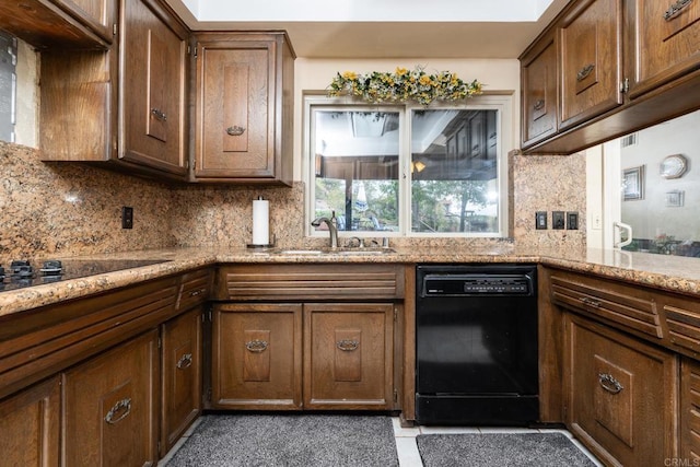 kitchen featuring light stone countertops, black appliances, tasteful backsplash, and a sink