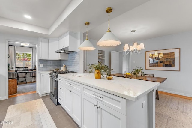 kitchen with stainless steel range with gas stovetop, white cabinets, a kitchen island, and decorative backsplash