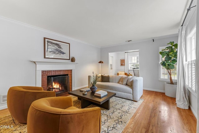 living room featuring visible vents, baseboards, light wood-type flooring, ornamental molding, and a fireplace