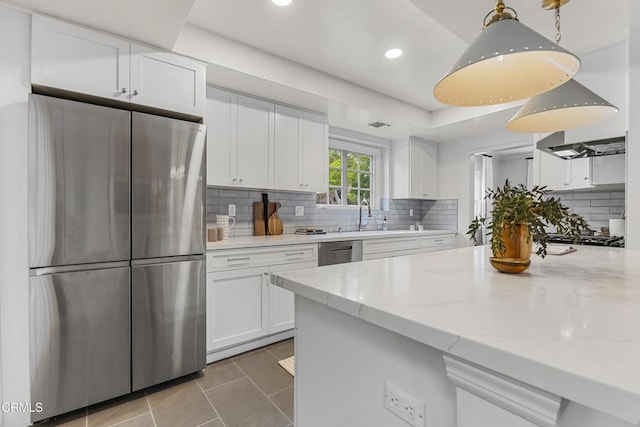 kitchen with light stone countertops, light tile patterned flooring, stainless steel appliances, decorative backsplash, and white cabinetry