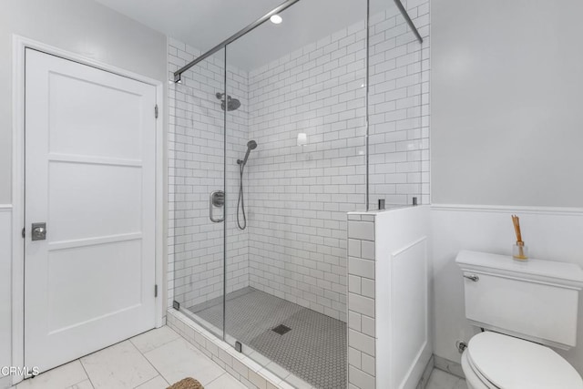 bathroom featuring marble finish floor, a stall shower, and toilet