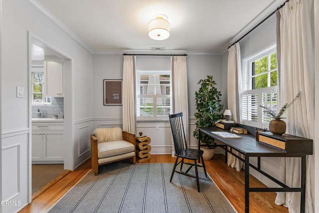 office space with wainscoting, plenty of natural light, light wood-style flooring, and ornamental molding