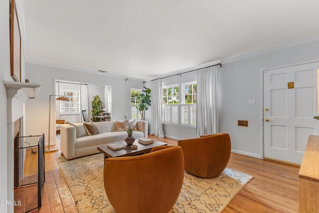 living area featuring visible vents, baseboards, ornamental molding, light wood-style flooring, and a fireplace