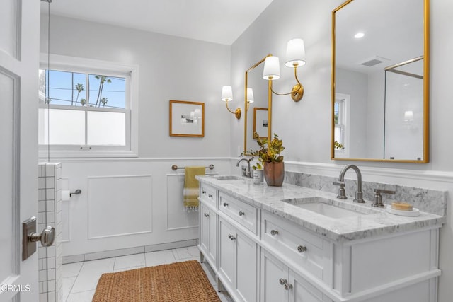 full bath featuring a wainscoted wall, a decorative wall, visible vents, and a sink