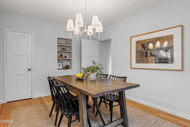 dining room with light wood-type flooring, baseboards, and a chandelier