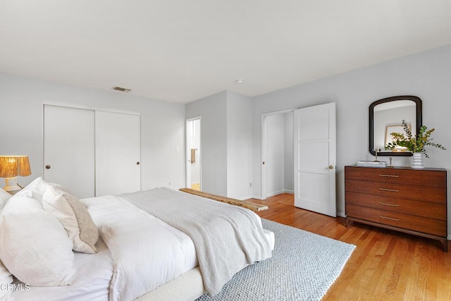 bedroom featuring light wood-style floors, visible vents, and a closet