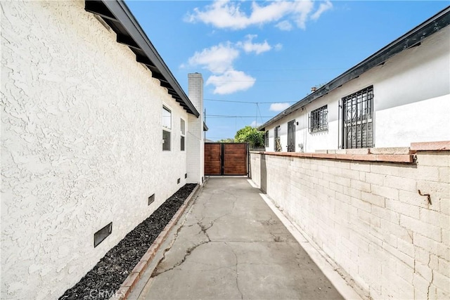 view of property exterior featuring crawl space, a chimney, fence, and stucco siding