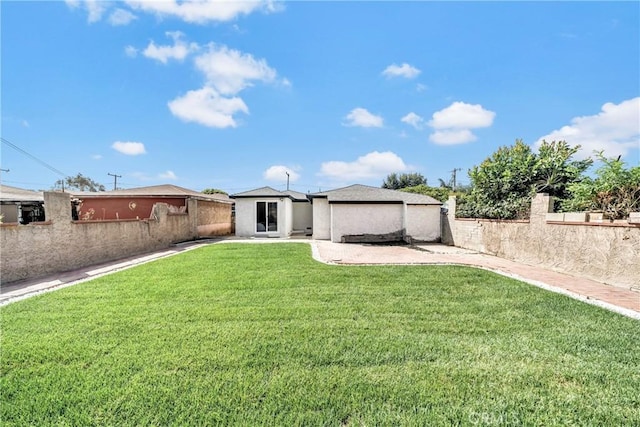 rear view of house featuring an outbuilding, a fenced backyard, a lawn, and stucco siding