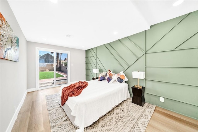 bedroom featuring access to exterior, wood finished floors, and baseboards