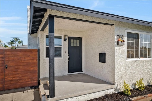 doorway to property featuring a patio area, fence, and stucco siding