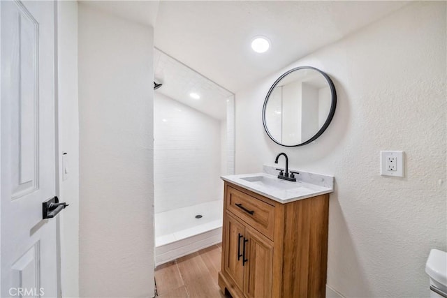 full bath featuring a textured wall, toilet, wood finished floors, vanity, and a shower stall