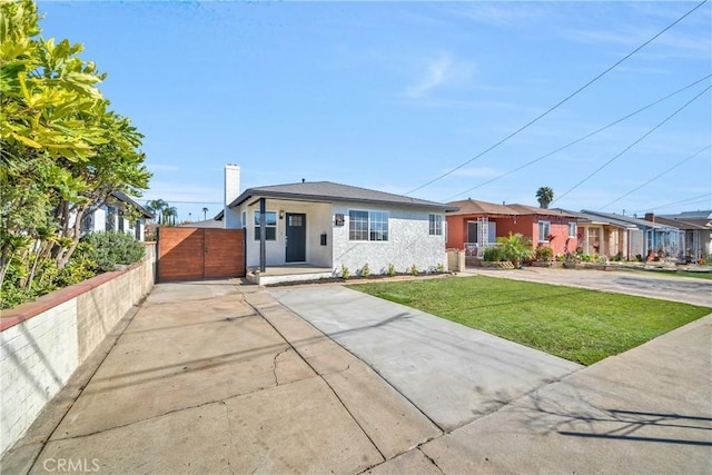 view of front facade with a gate, driveway, a front lawn, and stucco siding