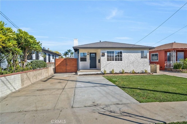 view of front of house featuring fence, a gate, stucco siding, a front lawn, and a chimney