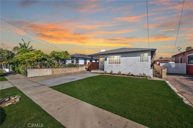 view of front of house featuring stucco siding, a gate, fence, and a yard