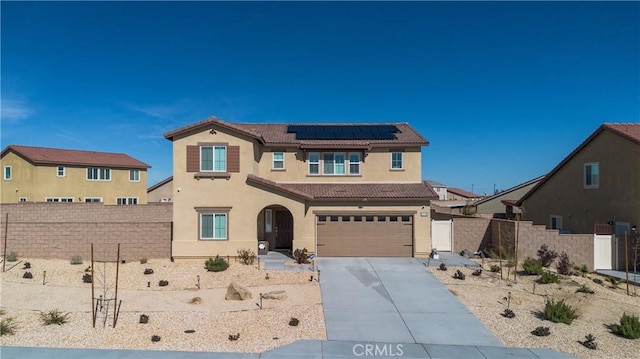 view of front of house with fence, a tiled roof, roof mounted solar panels, stucco siding, and driveway