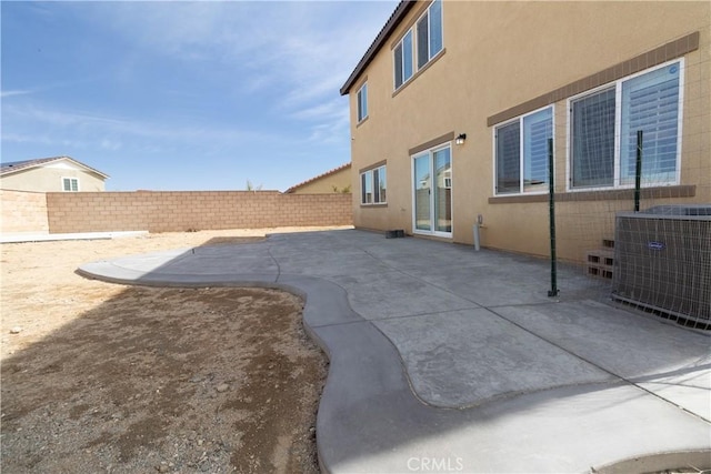 rear view of house with stucco siding, a fenced backyard, cooling unit, and a patio area