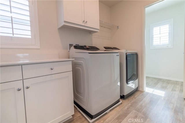 washroom with baseboards, cabinet space, independent washer and dryer, and light wood-style flooring