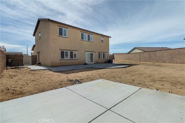 rear view of property featuring a patio, a fenced backyard, and stucco siding