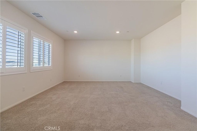 spare room with baseboards, recessed lighting, visible vents, and light carpet