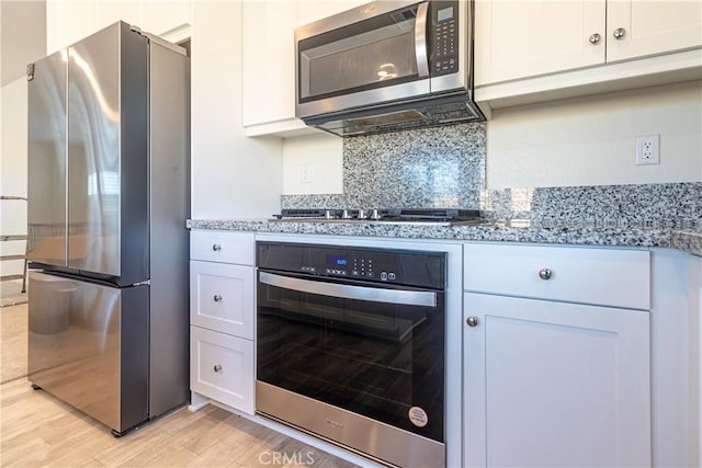 kitchen featuring light wood-style flooring, white cabinetry, stainless steel appliances, and light stone countertops