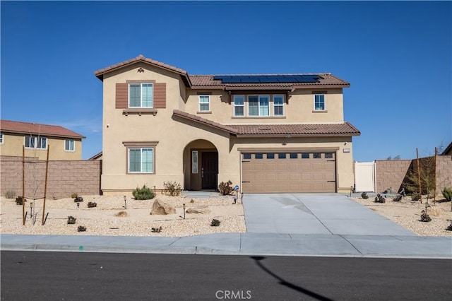 mediterranean / spanish-style home with fence, a tiled roof, concrete driveway, roof mounted solar panels, and stucco siding