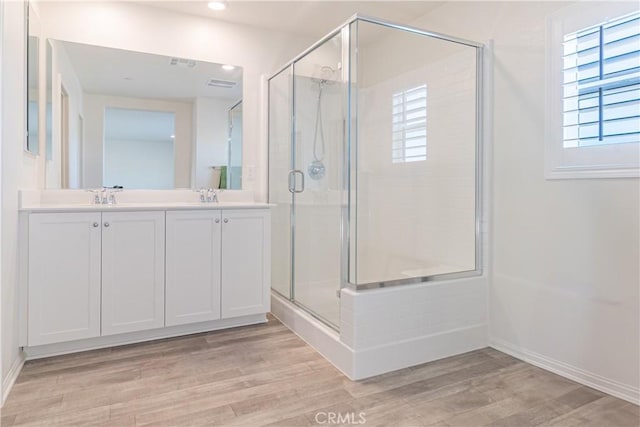 full bath featuring a healthy amount of sunlight, wood finished floors, a shower stall, and a sink