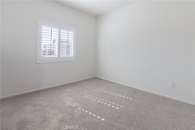 carpeted spare room featuring baseboards