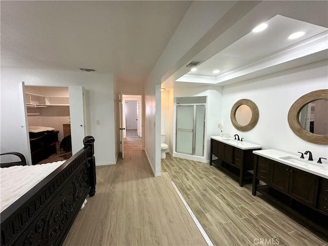 bathroom with wood finished floors, a shower stall, toilet, a sink, and visible vents