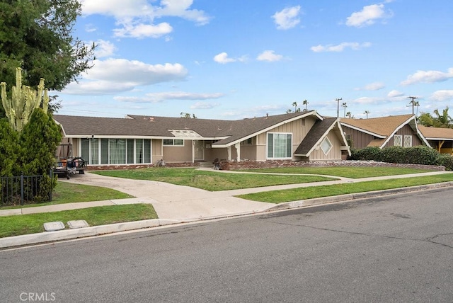 view of front of house with stone siding, concrete driveway, and a front lawn