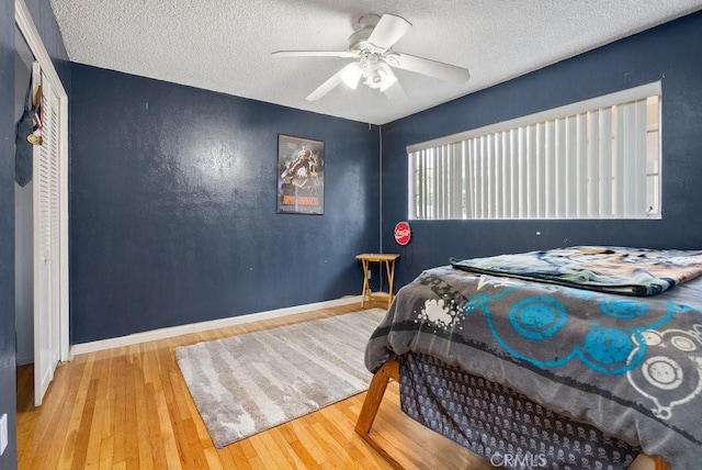 bedroom featuring a textured ceiling, baseboards, and wood-type flooring