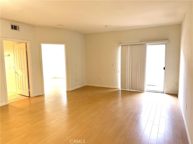 unfurnished room with visible vents, light wood-style flooring, and baseboards