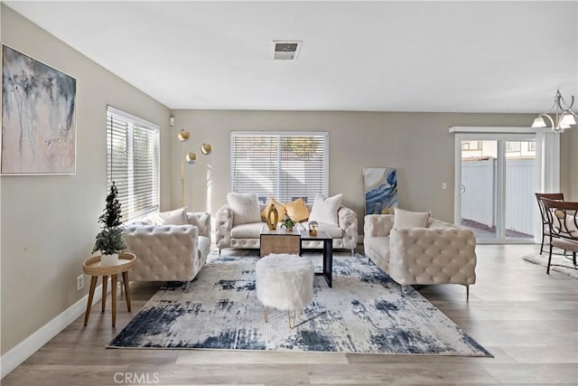 living room with baseboards, wood finished floors, and a notable chandelier