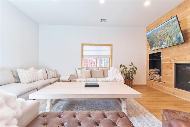 living room with a glass covered fireplace, visible vents, light wood finished floors, and recessed lighting