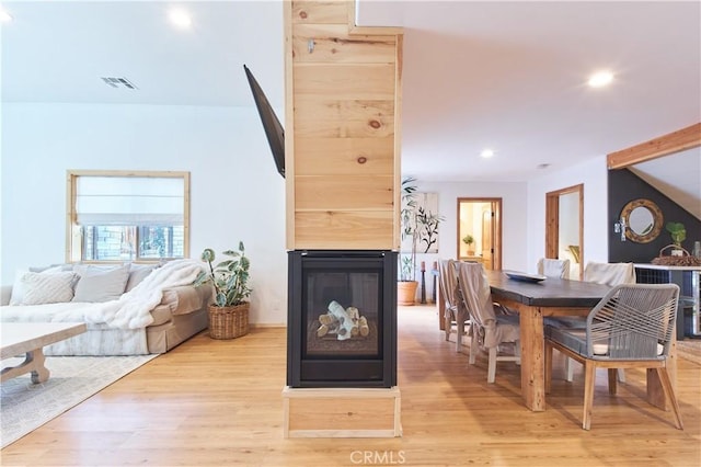 dining space featuring light wood-style floors, recessed lighting, visible vents, and a multi sided fireplace