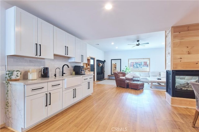 kitchen featuring light countertops, a sink, light wood-style flooring, and white cabinetry