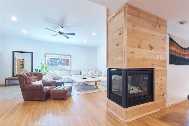 living room with visible vents, a ceiling fan, wood finished floors, a multi sided fireplace, and recessed lighting