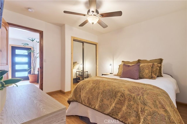 bedroom with light wood-style floors, ceiling fan, baseboards, and a closet