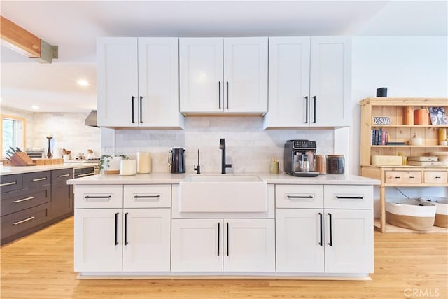 kitchen with backsplash, white cabinetry, light countertops, and a sink