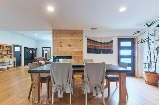 dining area featuring visible vents, a multi sided fireplace, light wood-style flooring, and recessed lighting