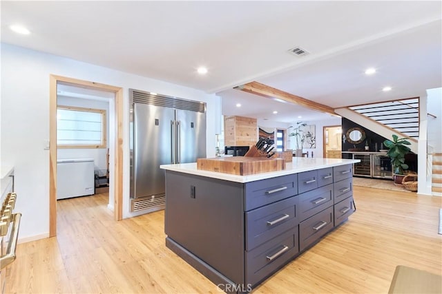 kitchen with light wood-style flooring, a center island, stainless steel built in fridge, and visible vents