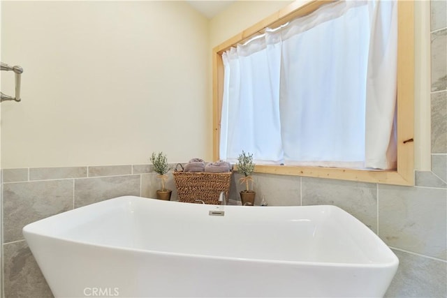 bathroom featuring a freestanding bath and tile walls