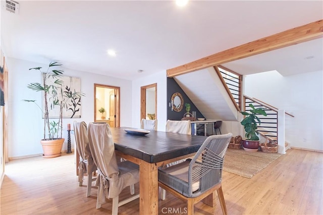 dining space featuring light wood-type flooring, visible vents, stairway, and lofted ceiling with beams